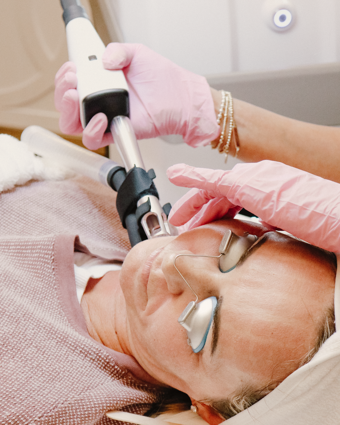 Person receiving a facial treatment with a device on a white background