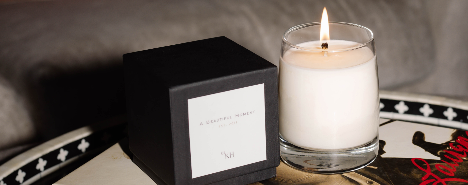 Candle in a glass holder with a black box labeled