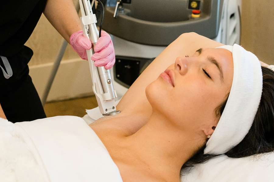 Woman receiving a cosmetic treatment with a machine held by a professional.