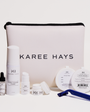 Karee Hays skincare set with a large white zippered pouch in the center, surrounded by skincare products including a serum bottle, toner, pads, and a blue razor on a clean white background.