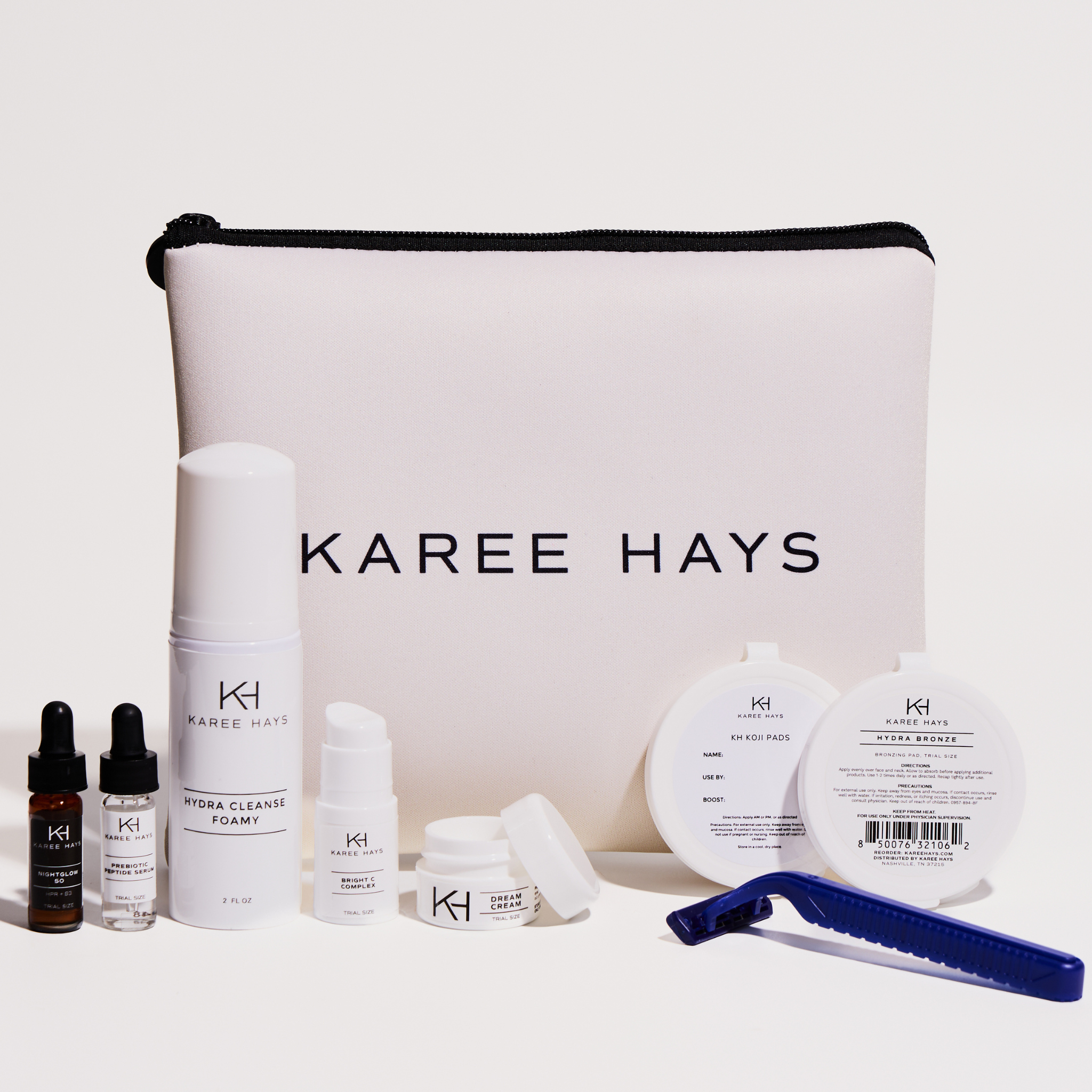 Karee Hays skincare set with a large white zippered pouch in the center, surrounded by skincare products including a serum bottle, toner, pads, and a blue razor on a clean white background.