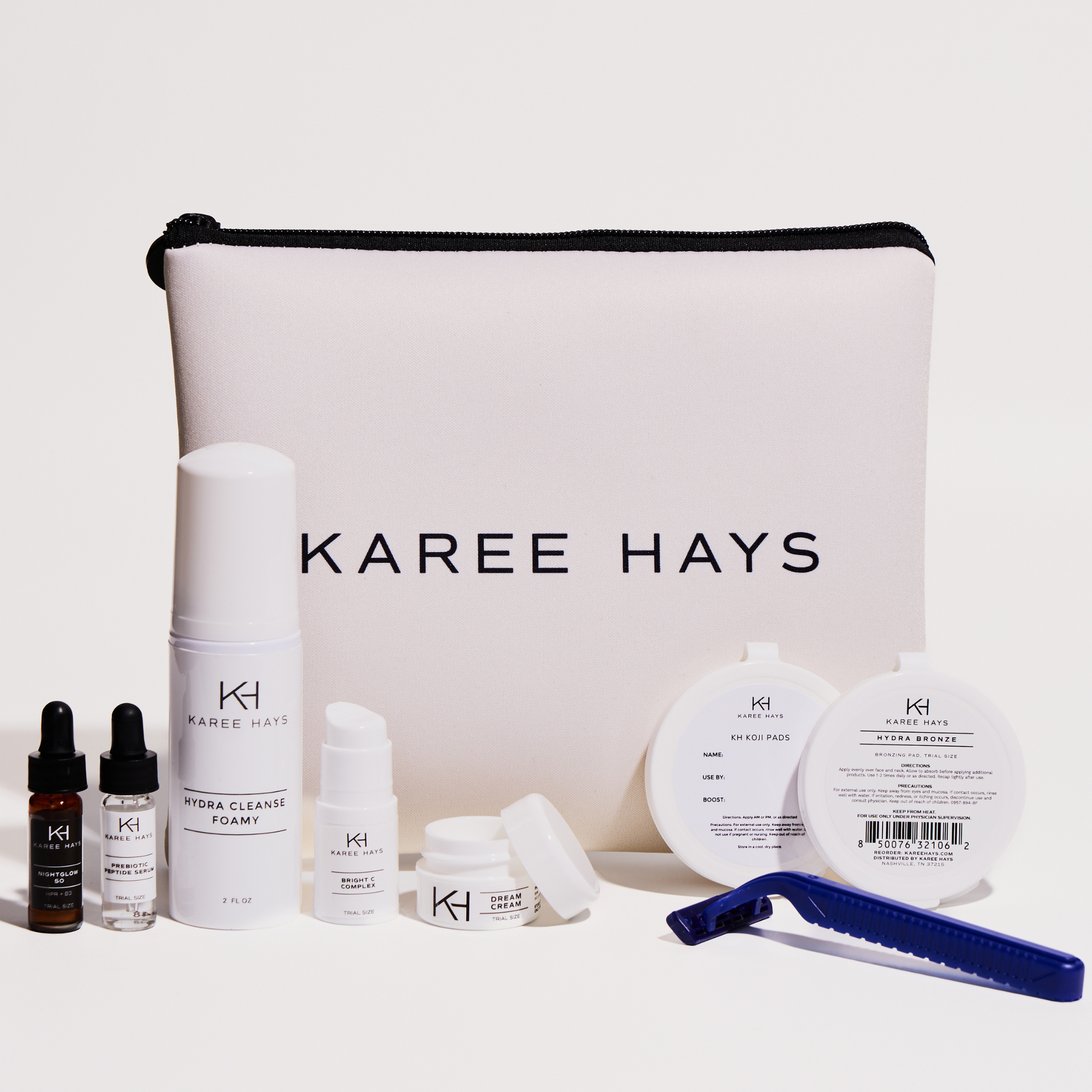 Karee Hays skincare set with a large white zippered pouch in the center, surrounded by skincare products including a serum bottle, toner, pads, and a blue razor on a clean white background.