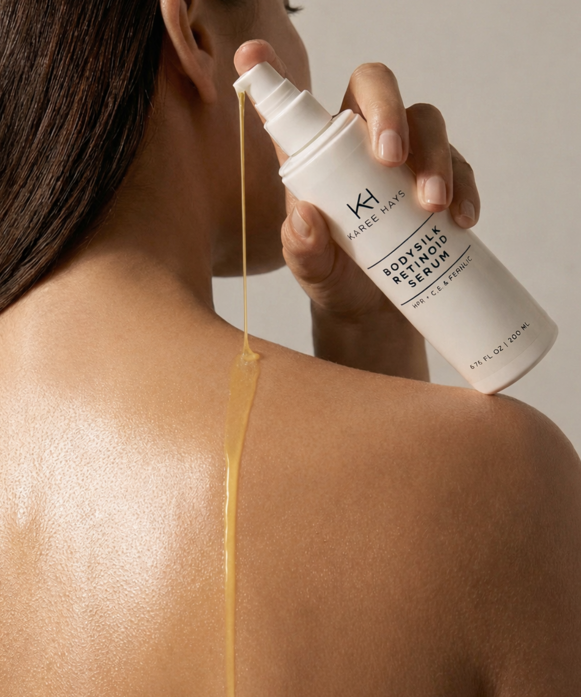 Person applying a skincare serum to their shoulder with KH Brand on the bottle.