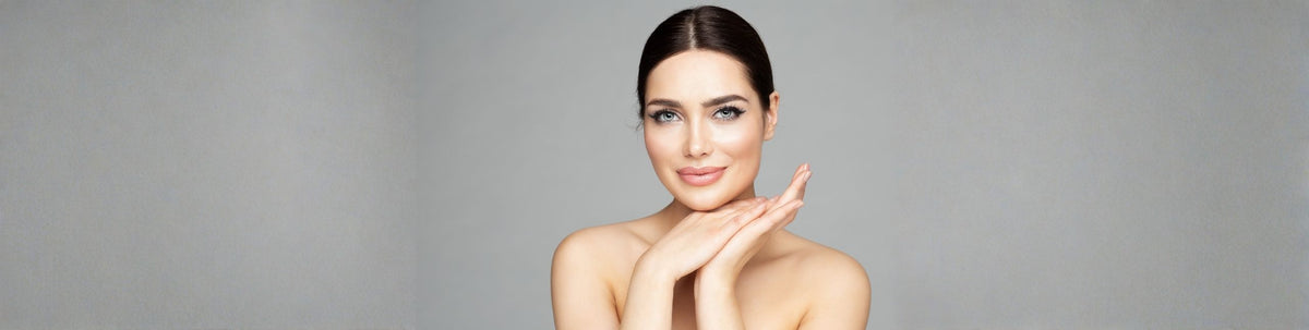 Woman with clear skin touching her face against a gray background